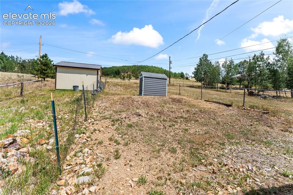 Image 17 of 20: Expansive outdoor area featuring a tan utility building with a metal roof,