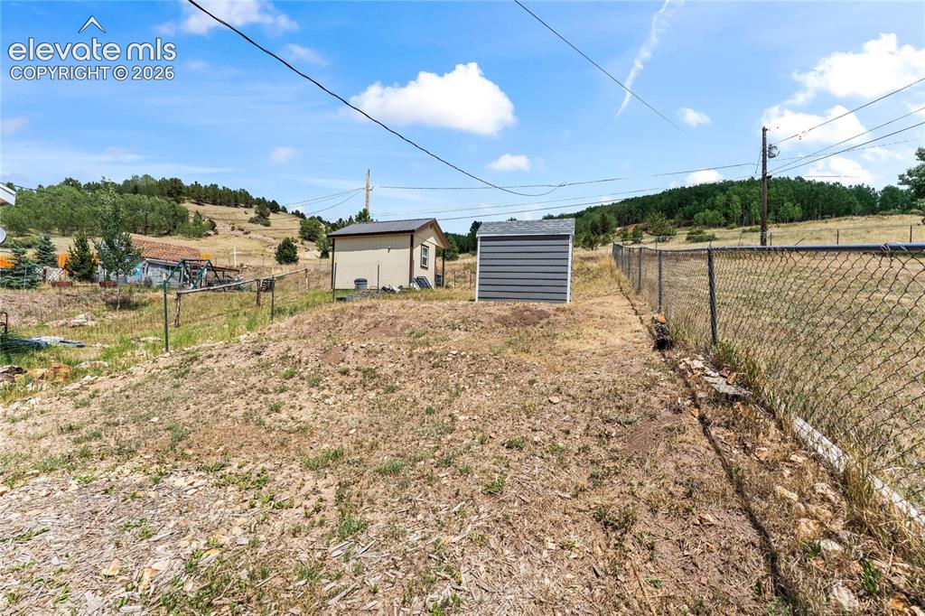 Image 18 of 20: Expansive outdoor space featuring a chain-link fence, a gray storage shed,