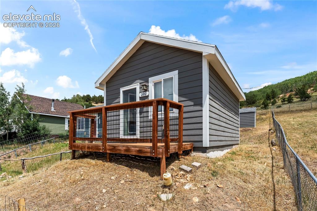 Image 2 of 20: Exterior featuring gray horizontal siding, white trim, and a wood deck with