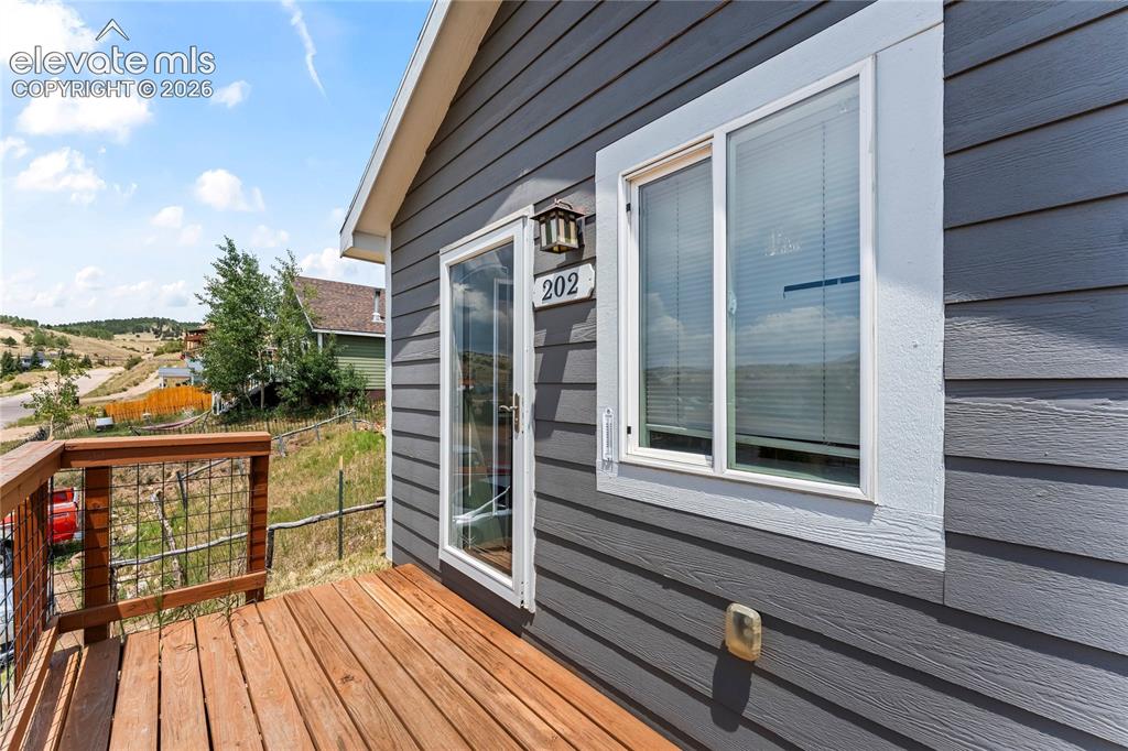 Image 3 of 20: Exterior featuring horizontal gray siding, a wood-finish deck with a metal