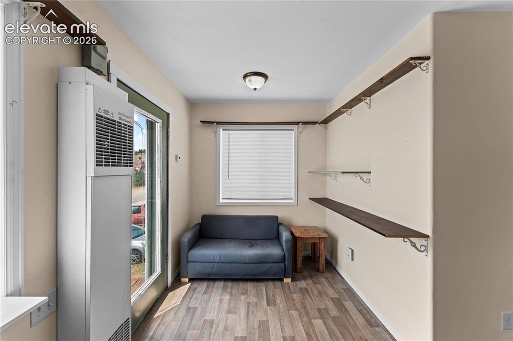 Image 7 of 20: Open concept room featuring wood-finish flooring, a wall-mounted heating un