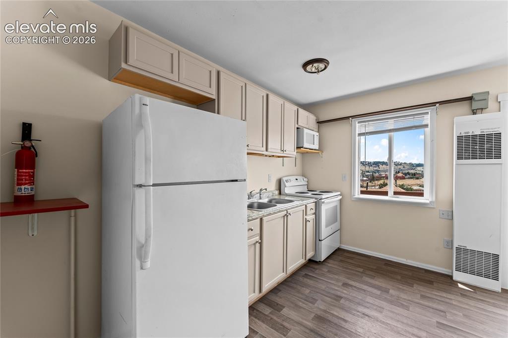 Image 9 of 20: Kitchen featuring wood-finish flooring, white appliances, light-toned cabin