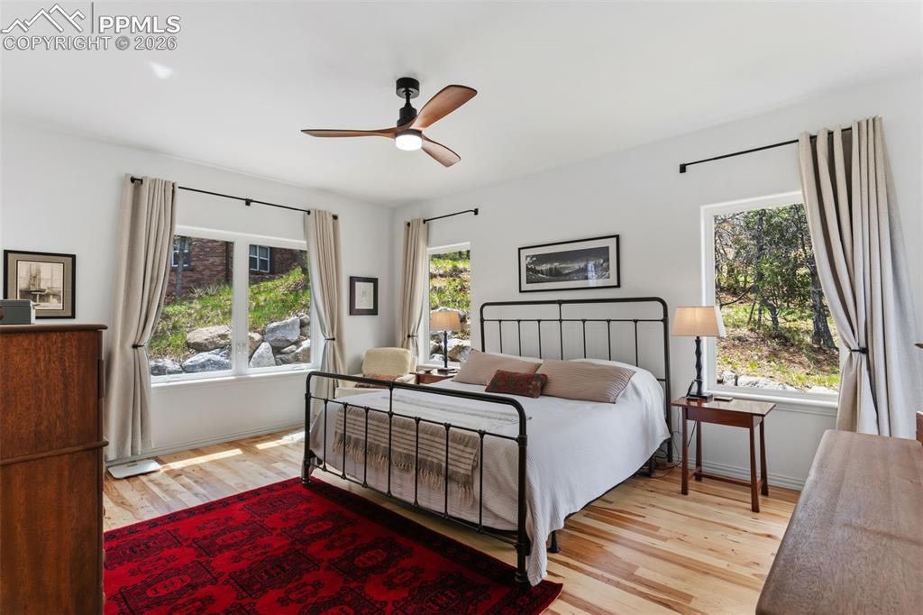 Image 21 of 49: Main level primary bedroom w/ hickory floors, large windows and a walk-out 