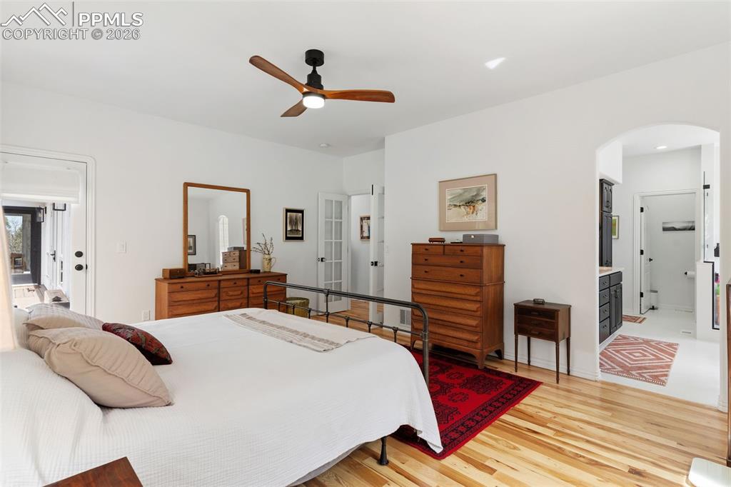 Image 22 of 49: Main level primary bedroom w/ hickory floors, French doors and a walk-out t
