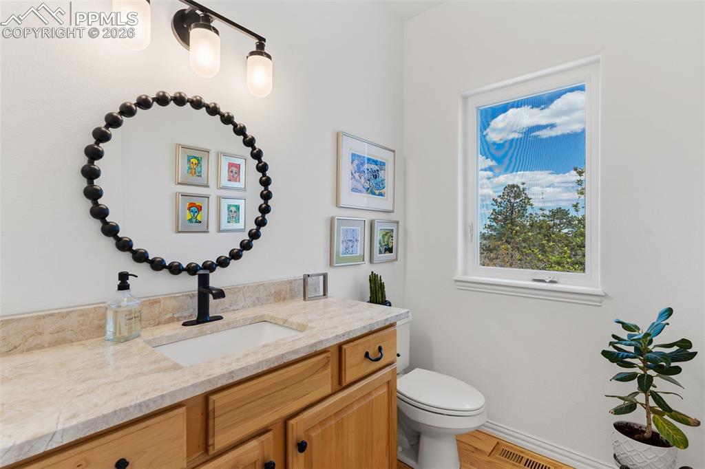 Image 24 of 49: Main level 1/4 Bathroom with Taj Majal quartzite countertop & hickory floor