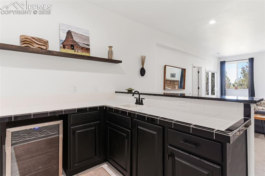 Image 30 of 49: Convenient wet bar with sink and bar fridge