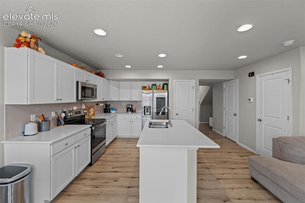 Image 10 of 32: Kitchen featuring white shaker cabinetry, stainless steel appliances, a cen