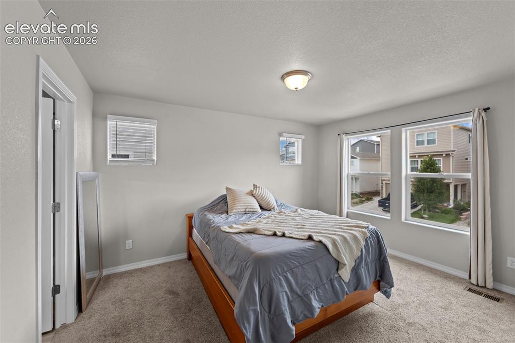 Image 12 of 32: Carpeted flooring, recessed lighting, and multiple windows with blinds