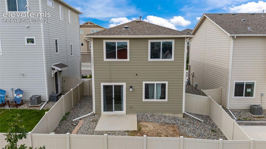 Image 19 of 32: Two-story residence with a tan siding exterior, multiple windows, and a sli