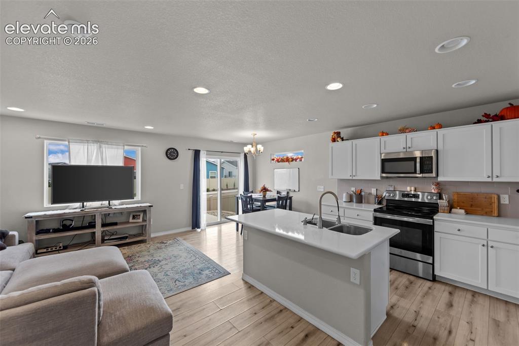 Image 5 of 32: Open-concept living space featuring wood-finish flooring, recessed lighting