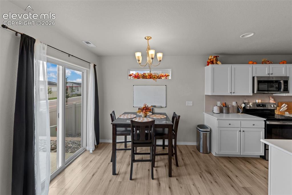 Image 7 of 32: Light wood-finish flooring throughout, a glass sliding door, and white uppe