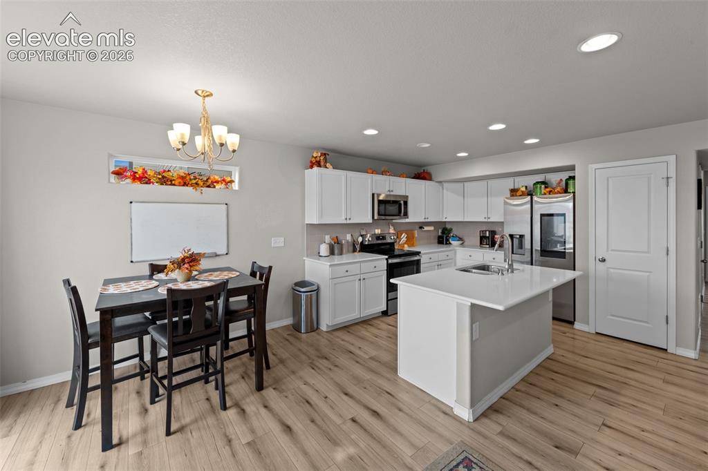 Image 8 of 32: Bright kitchen with white cabinetry, stainless steel appliances, a center i