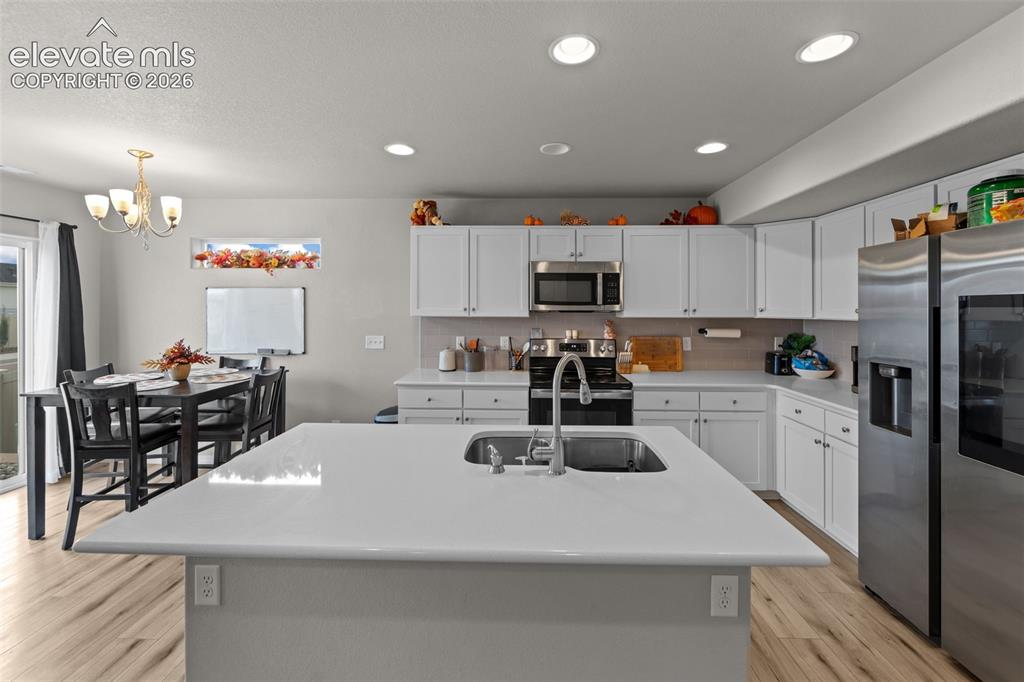 Image 9 of 32: Kitchen featuring a large island with an undermount sink, white cabinetry, 