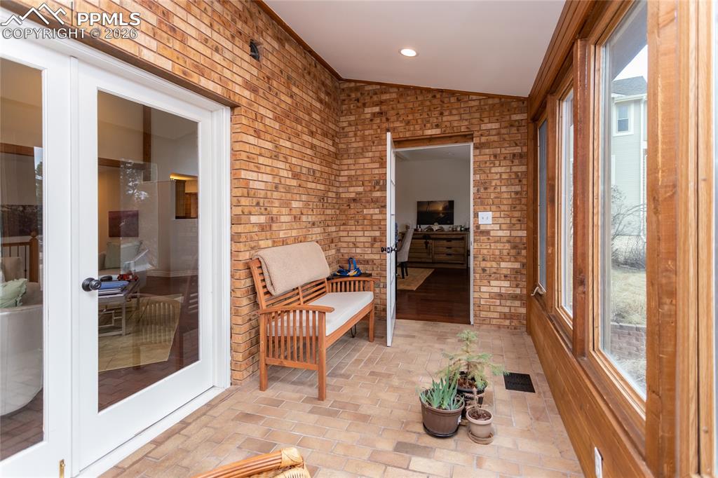 Image 21 of 45: The light filled sun room with floor to ceiling windows accessed from the l