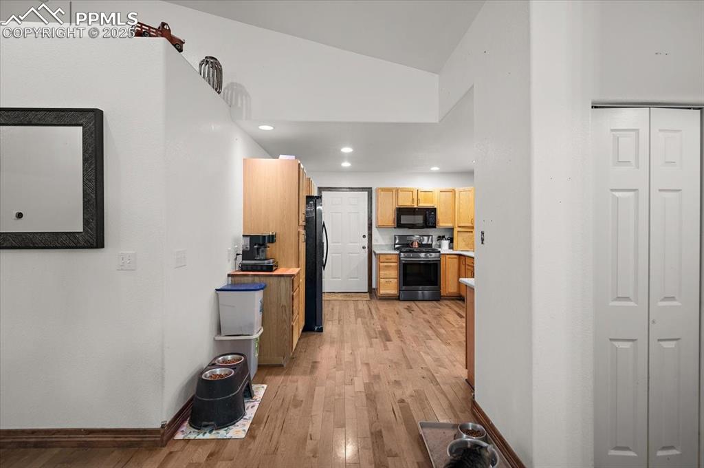Image 10 of 38: Corridor featuring light wood finished floors, lofted ceiling, baseboards,