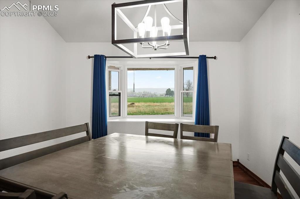 Image 12 of 38: Unfurnished dining area featuring a chandelier, baseboards, and dark wood-t