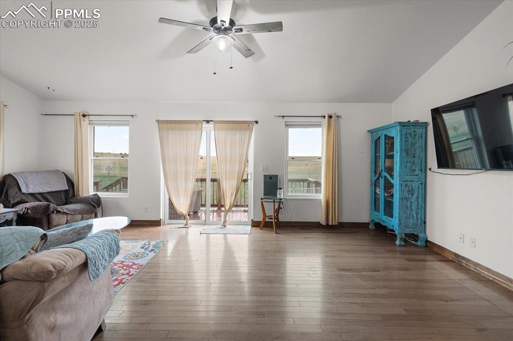 Image 13 of 38: Living area with a ceiling fan, hardwood / wood-style floors, baseboards, a