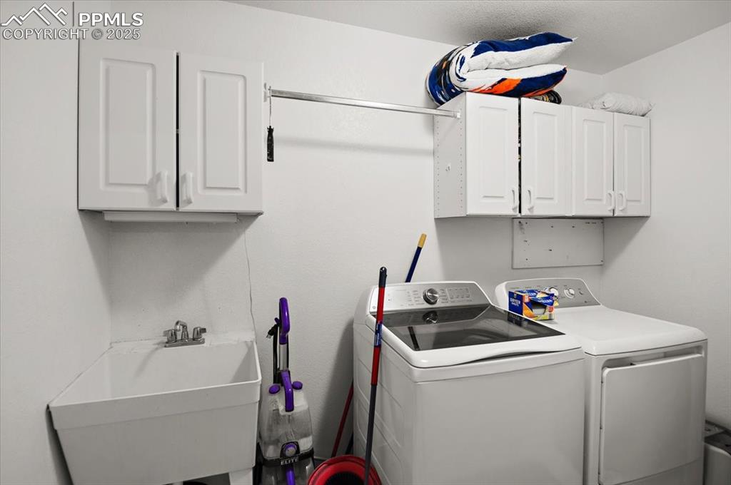 Image 20 of 38: Laundry area featuring washing machine and dryer and cabinet space