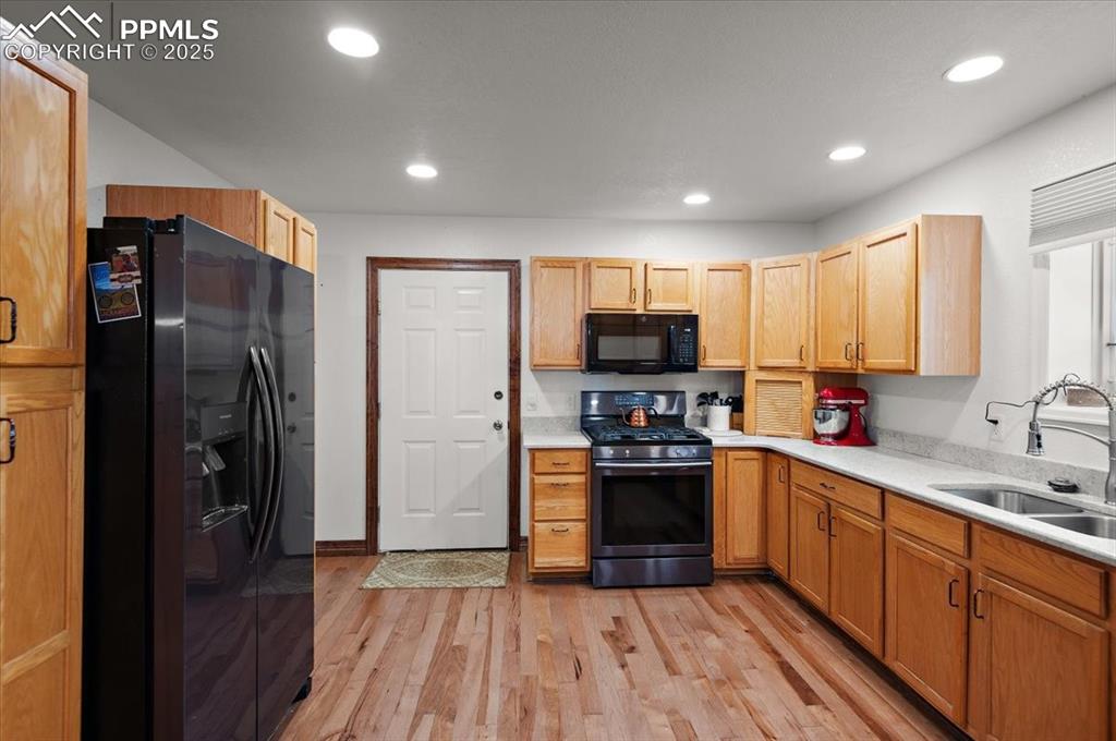 Image 5 of 38: Kitchen with black appliances, a sink, light countertops, light wood finish