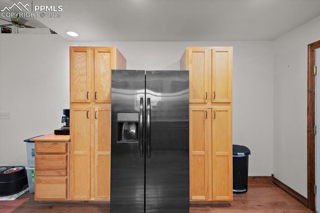 Image 6 of 38: Kitchen with black fridge with ice dispenser, wood finished floors, light b