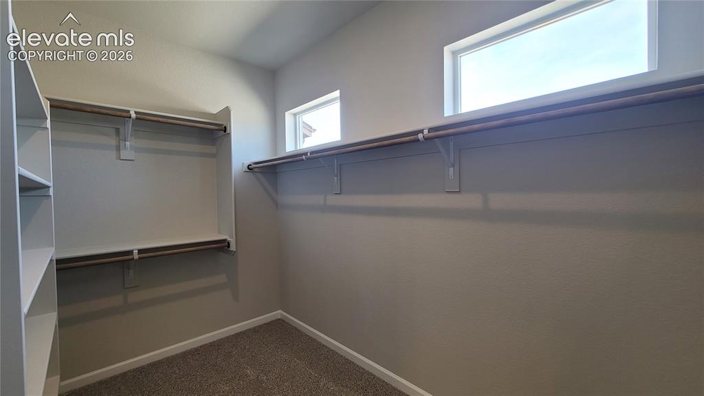 Image 29 of 50: 1 of 2 Primary Walk-in closets with wood shelving and rods!