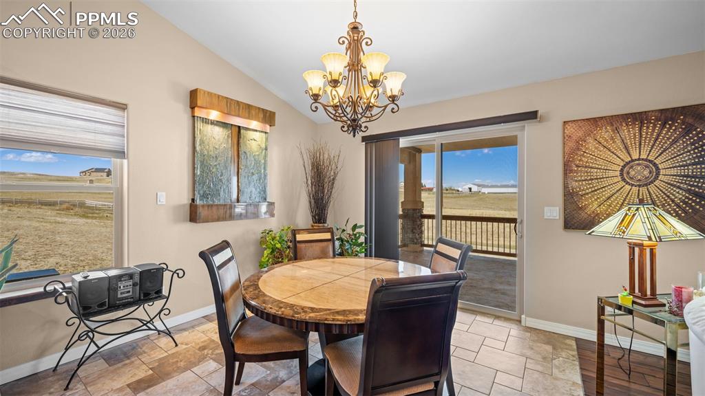 Image 10 of 47: Dining room featuring hanging lights, stone tile flooring, and lofted ceili