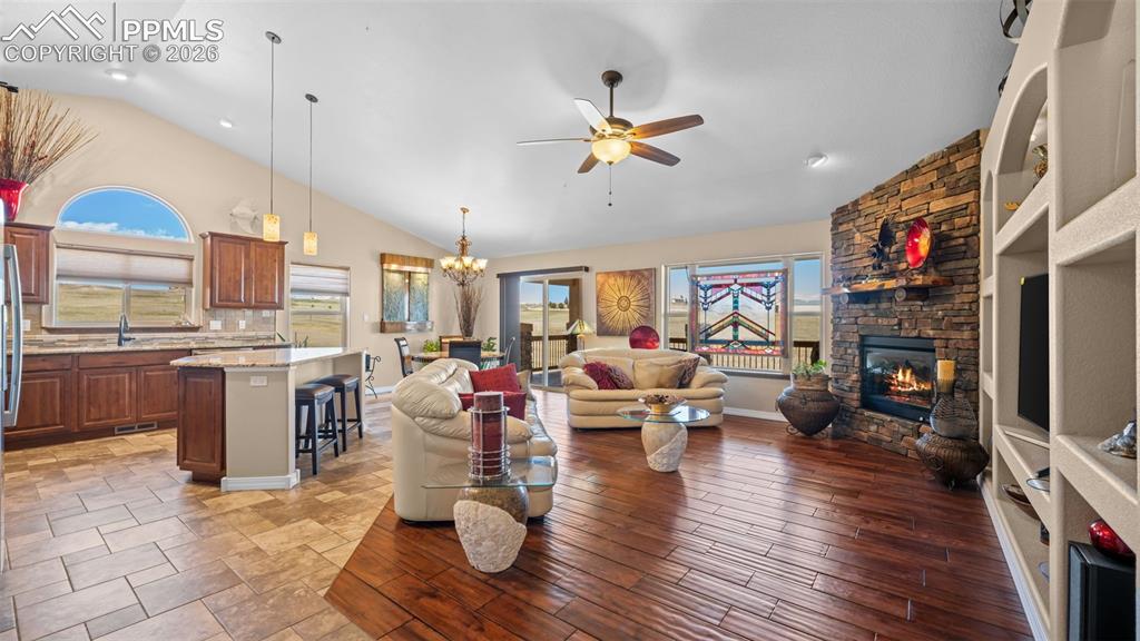 Image 13 of 50: Living area with vaulted ceiling, a ceiling fan, suspended lighting, and a