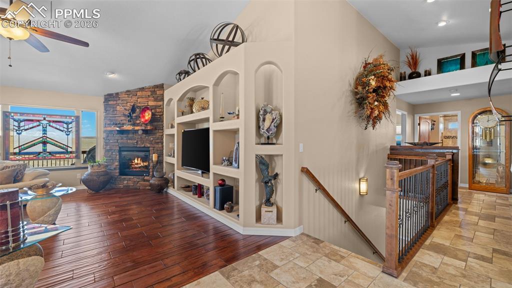 Image 14 of 50: Living room featuring lofted ceiling, built in features, a stone fireplace,