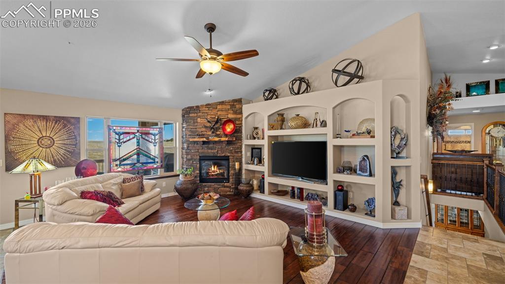 Image 15 of 50: Living area featuring a fireplace, a ceiling fan, hardwood / wood-style flo