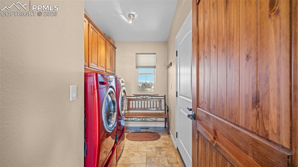 Image 16 of 47: Laundry room featuring stone finish flooring, cabinet space, washer/dryer a
