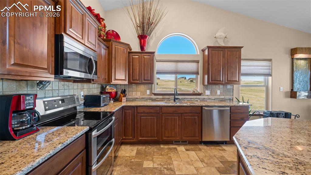 Image 18 of 47: Kitchen with stainless steel appliances, stone finish flooring, lofted ceil