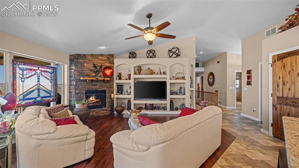 Image 18 of 50: Living room with a ceiling fan, plenty of natural light, a fireplace, stone