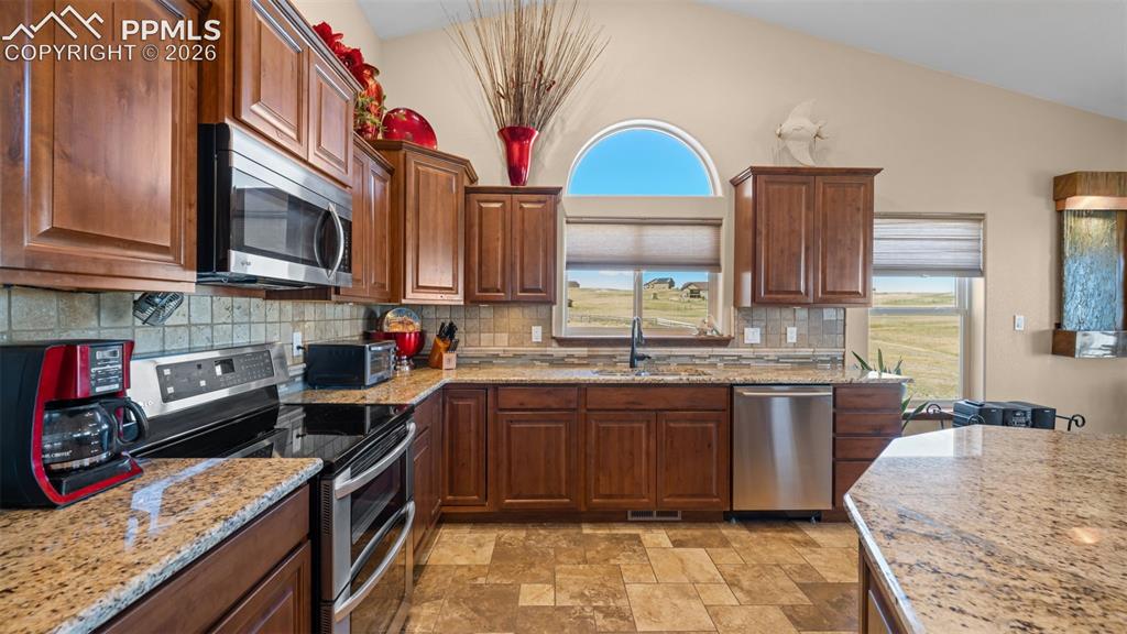 Image 19 of 50: Kitchen with stainless steel appliances, stone finish flooring, lofted ceil