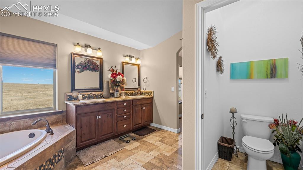 Image 24 of 50: Bathroom with double vanity, a garden tub, and light stone finish flooring