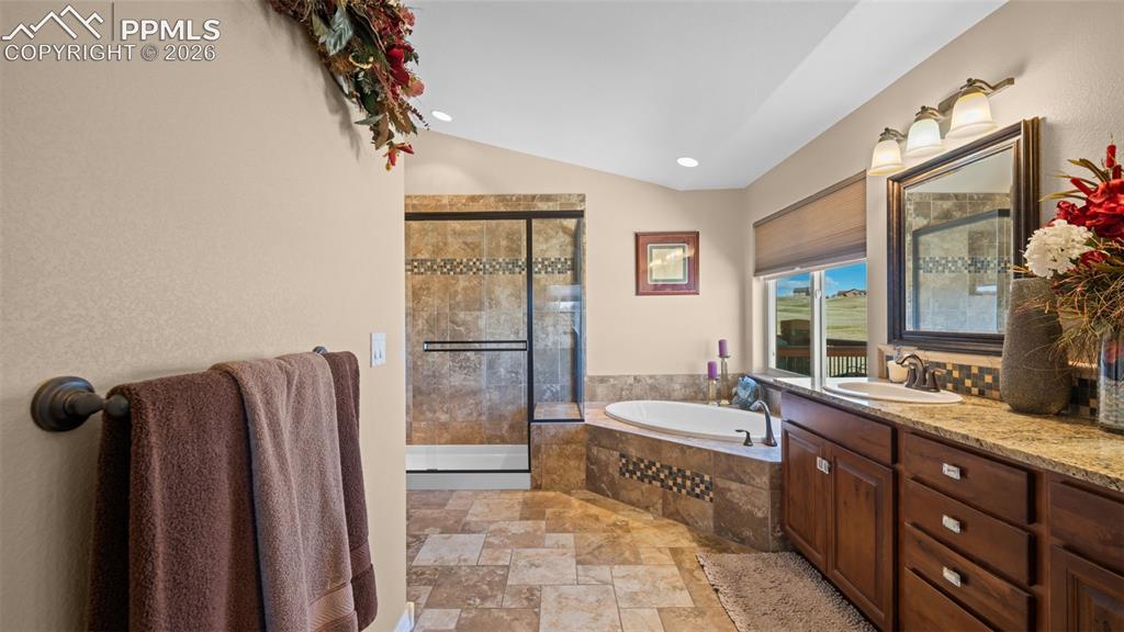 Image 26 of 50: Bathroom with a shower stall, lofted ceiling, light stone finish floors, a