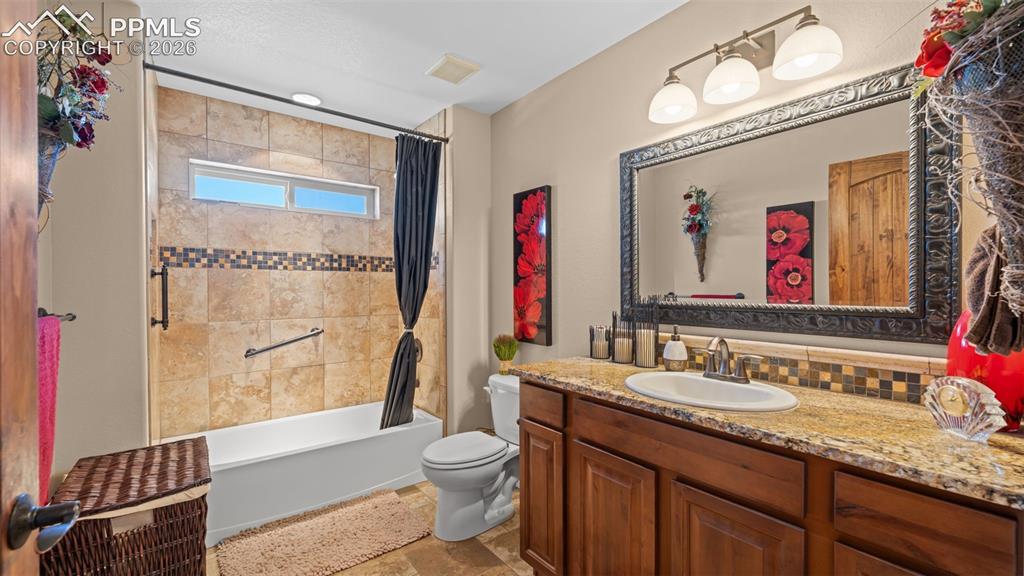 Image 30 of 50: Bathroom featuring vanity, light stone finish flooring, shower / bath combo