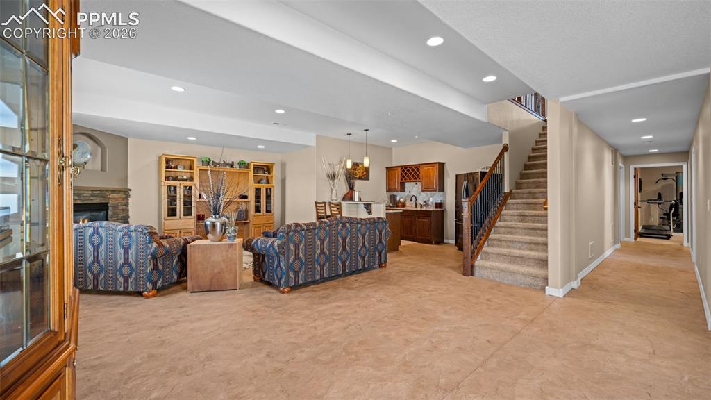 Image 31 of 50: Living area with a fireplace, recessed lighting, terrific wet bar, polished