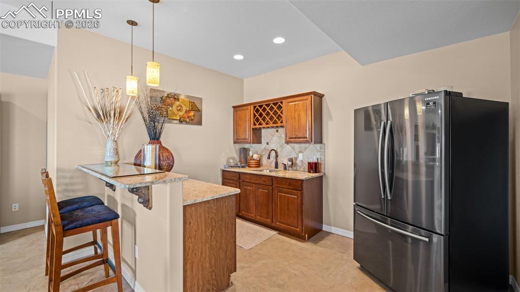 Image 32 of 47: Wet bar with freestanding refrigerator, bar top, a peninsula, wood finish c