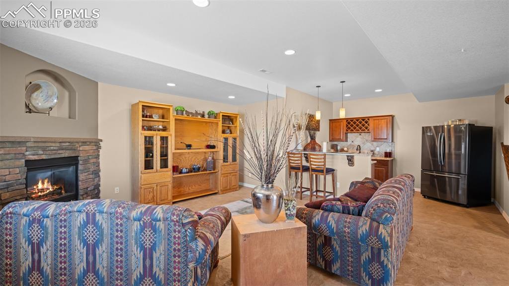 Image 32 of 50: Living area featuring a fireplace, polished, stamped concrete flooring, wet