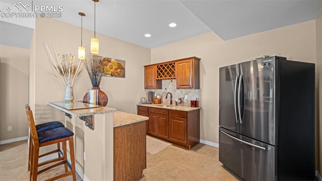 Image 33 of 50: Wet bar with freestanding refrigerator, bar top, a peninsula, wood finish c