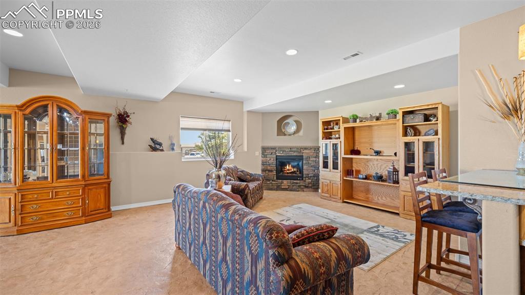 Image 34 of 47: Living area with a stone fireplace and recessed lighting