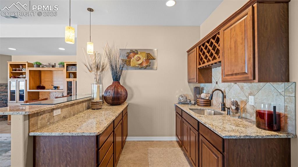 Image 34 of 50: Gorgeous wet bar with a peninsula, light stone counters, backsplash, decora