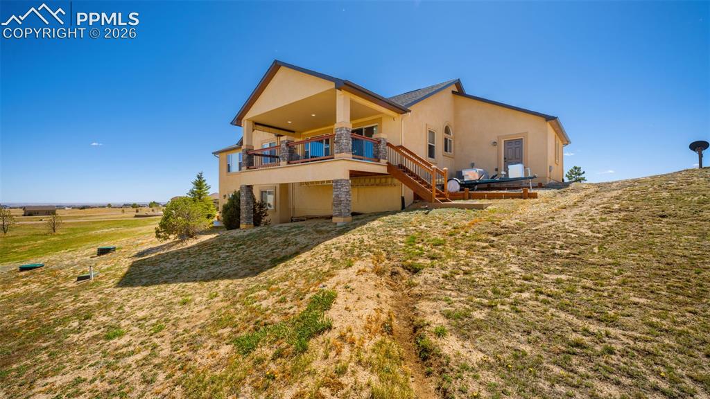 Image 43 of 50: Rear view of property with stucco siding, deck, and yard