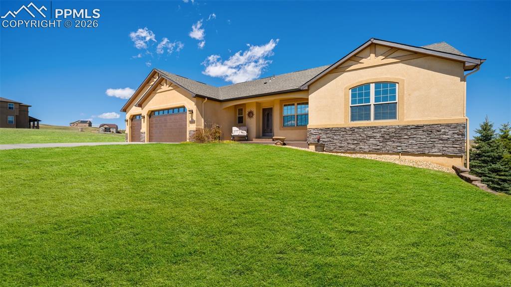 Image 46 of 50: View of front of home with stucco and stone an attached 3 car garage, a fro