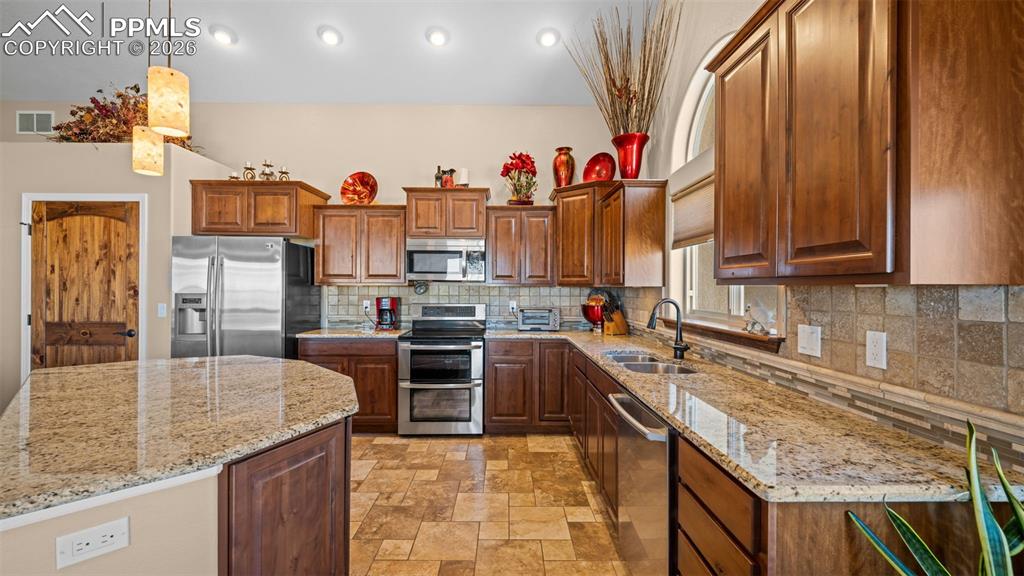 Image 7 of 47: Kitchen featuring stainless steel appliances, a kitchen island, decorative 