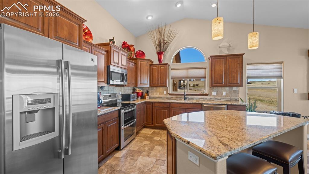 Image 9 of 50: Kitchen with stainless steel appliances, a kitchen breakfast bar, hanging l