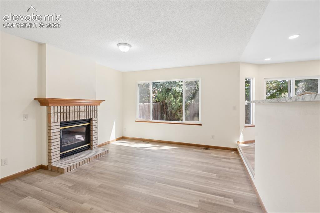 Image 4 of 41: Cozy family room with gas fireplace open to kitchen.