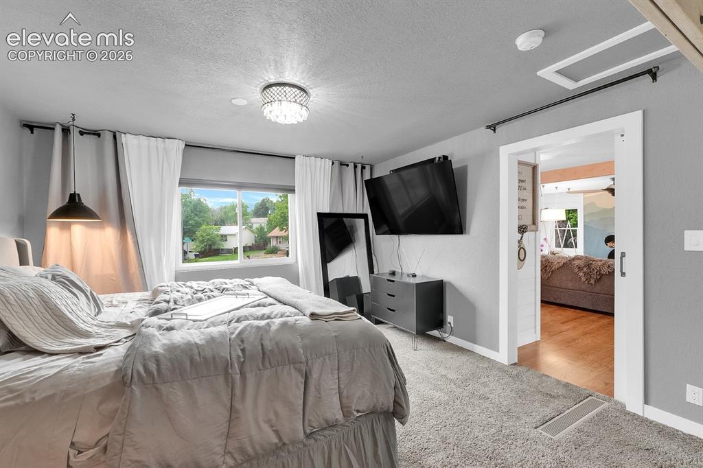 Image 11 of 33: Carpeted bedroom featuring a large window, a crystal flush mount ceiling li