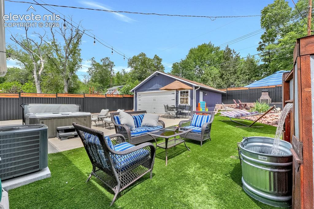 Image 23 of 33: Expansive backyard featuring artificial turf, a concrete patio, and a hot t