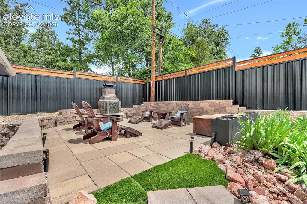 Image 25 of 33: Paved patio featuring a built-in stone fire pit, stone retaining walls, pri